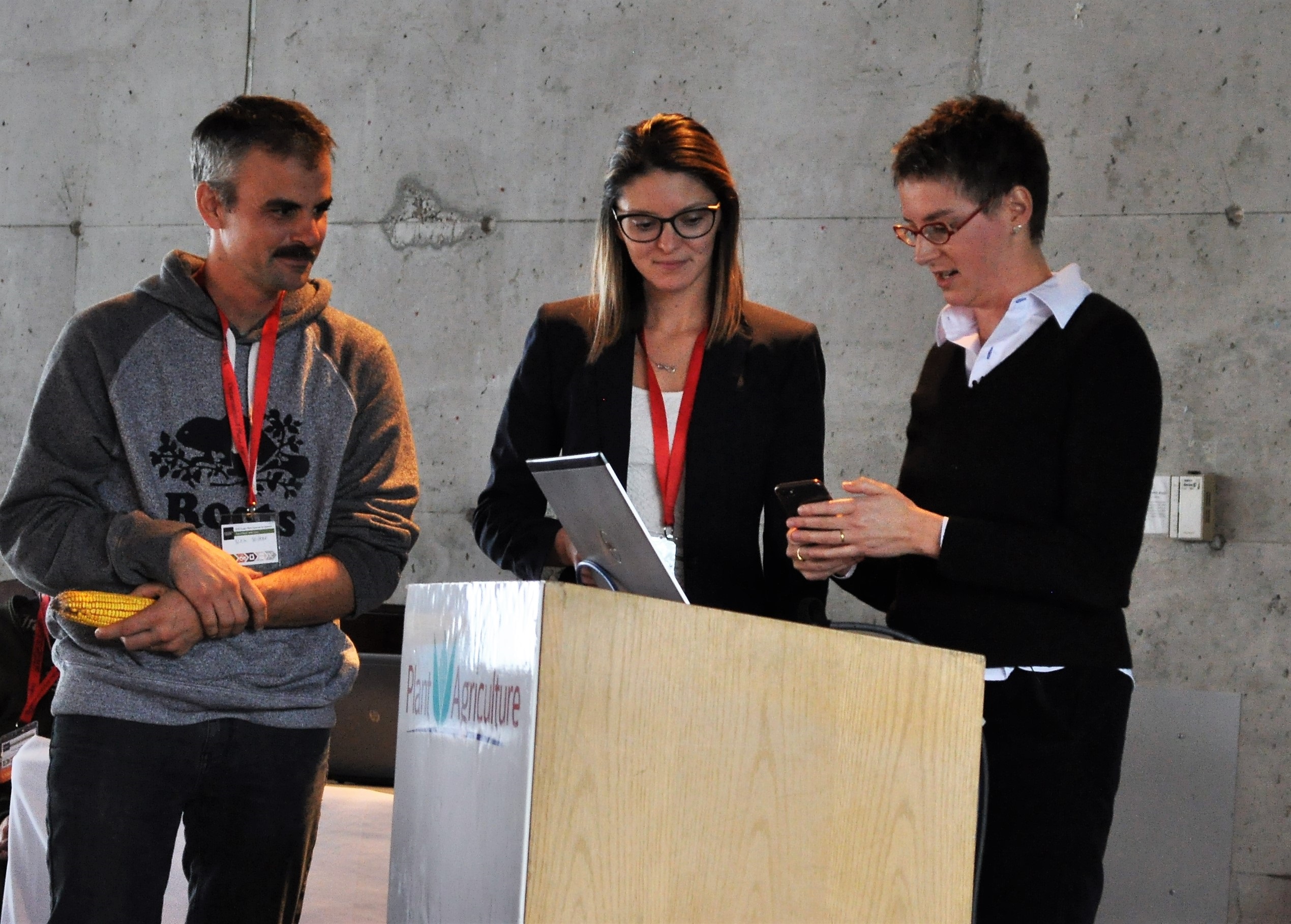 2 Women and a Man standing at a Podium